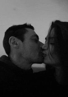 a man and a woman kissing in a black and white photo