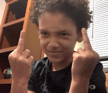 a young boy giving the middle finger in front of a window