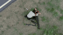 an aerial view of a police officer kneeling over a dead man