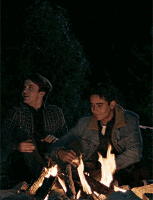 two men sit around a fire at night