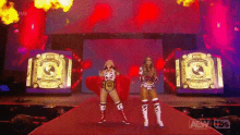 two female wrestlers are walking down a red carpet with a aew logo in the background