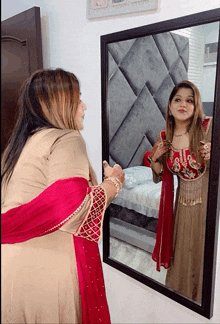 a woman in a red dress looks at herself in a mirror