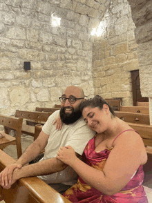 a man with glasses and a beard sits next to a woman in a church