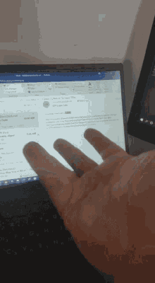 a person 's hand is reaching out to touch a laptop screen