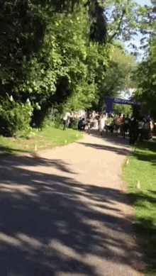 a group of people are walking down a path in a park with a sign that says ' sydney ' on it