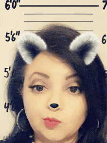 a woman wearing a cat ear filter is standing in front of a wall that says 6 '0 "