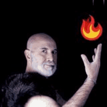 a man with a beard is holding a fireball in his hand in front of a black background .