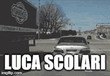 a car is driving down a street with the words luca scolari written on the bottom