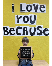 a young boy holding a sign that says i love you because