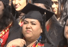 a group of women wearing graduation caps and gowns are standing in a line .