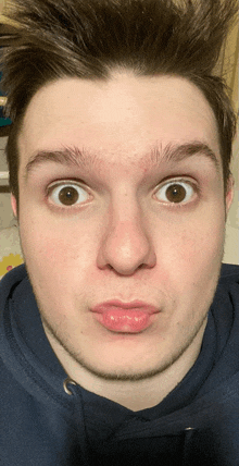 a close up of a man 's face with a blue sweatshirt on