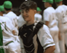 a group of baseball players are standing in a line and one of them is wearing a catcher 's mitt .