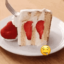 a slice of cake with strawberries and whipped cream on a plate with a smiley face next to it .