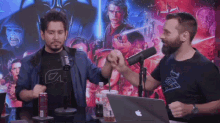 two men giving each other a fist bump in front of a poster of darth vader