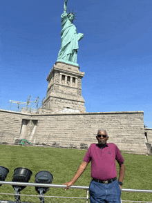 a man stands in front of the statue of liberty in new york city