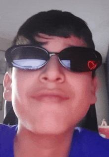 a young boy wearing sunglasses with a heart on the lens