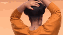 a woman with a tattoo on the back of her neck is wearing an orange sweater with crowned ladies written on it