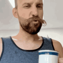 a man with a beard and mustache is drinking from a mug