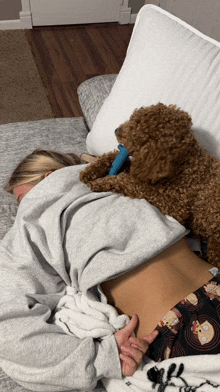 a woman is laying on a bed with a small brown dog on her back