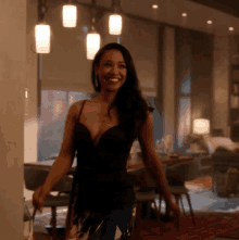 a woman in a black dress is standing in a room smiling