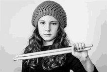 a black and white photo of a young girl holding drumsticks .