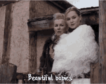 two women standing in front of a building with the words beautiful babies written on the bottom