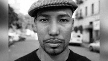 a black and white photo of a man wearing a hat and mustache .