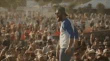 a man with a beard is singing into a microphone in front of a crowd at a music festival .