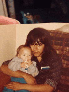 a woman holds a baby in her arms and the baby is drinking from a bottle