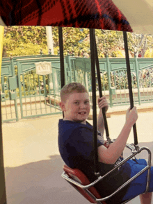 a boy is sitting on a swing with an exit sign in the background