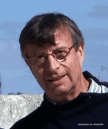 a man wearing glasses and a sweater with the words vacances en charente on the bottom right