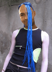 a man with blue hair is wearing a black tank top with a star on it