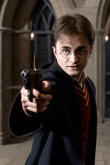 harry potter is holding a gun with a bullet pointing at the camera