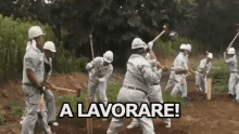 a group of construction workers are holding hammers in a field with the words a lavorare written above them .