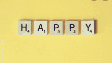 scrabble tiles arranged to spell the word happy on a yellow background