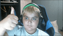 a boy wearing headphones gives a thumbs up