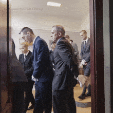 a group of men in suits are standing in a room with the words la guarimba film festival on the ceiling