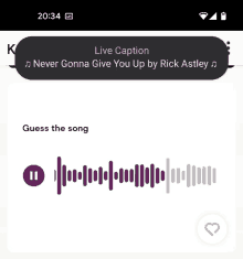 a phone screen shows a live caption of a song called never gonna give you up by rick astley