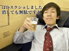 a man in a striped shirt and tie holds a cup of beer