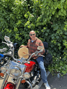 a man sits on a red motorcycle playing a drum