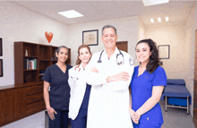 a group of doctors and nurses pose for a picture in a hospital room