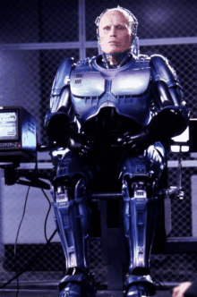 a man in a robot suit is sitting in front of a monitor that says ' ii ' on it