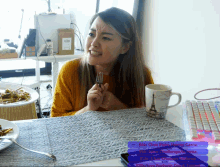 a woman sitting at a table with a fork in her hand and a mug with the eiffel tower on it