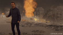 a man stands in front of an explosion with gifrun.com at the bottom of the screen