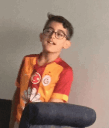 a boy wearing glasses and a red and orange shirt with a g on it