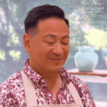 a man in a floral shirt is smiling in front of a sign that says the great canadian baking show