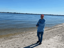 a man in a red hat is standing on a beach near the water