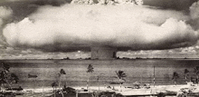 a black and white photo of a nuclear explosion over a beach .