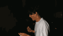 a young man in a white shirt is standing in the dark