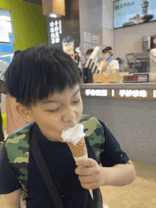 a young boy eating an ice cream cone in front of a sign that says ' chinese ' on it